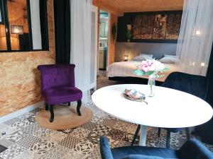 une chambre d'hôtel avec une chaise violette et une table dans l'établissement le Ti'Cocoon, à Langueux