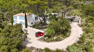 une vue aérienne sur une voiture rouge garée devant une maison dans l'établissement Mas d'Olea, à Lauris