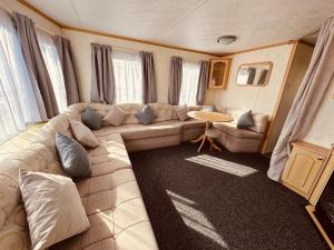 a living room with a couch and a table at Golden Sands Caravan Hire Ingoldmells- FREE in caravan wifi- Access included to the on site club house, sports bar, arcade, coffee shop We have beach access, a fishing lake and a laundrette in Ingoldmells