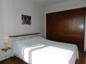 um quarto com uma cama branca e um armário de madeira em Appartement Bormes-les-Mimosas, 2 pièces, 4 personnes - FR-1-251-807 em Bormes-les-Mimosas