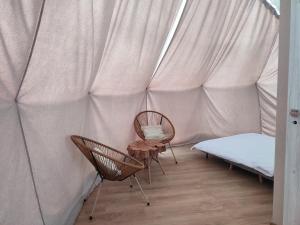 dwa krzesła i łóżko w namiocie w obiekcie Forrest Glamp w mieście Mieroszów
