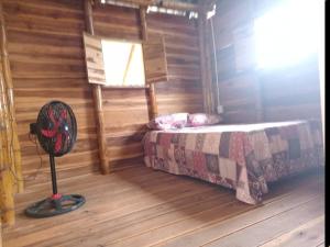 Oso Hostel Cabaña Santa Marta في سانتا مارتا: غرفة نوم بسرير ومروحة في الغرفة