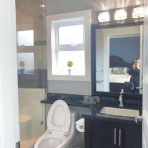 a bathroom with a toilet and a sink and a mirror at Comfortable suite for guests to use independently in Burnaby