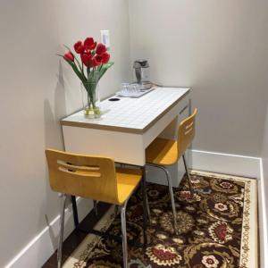 uma pequena mesa com duas cadeiras e um vaso de flores em Comfortable suite for guests to use independently em Burnaby