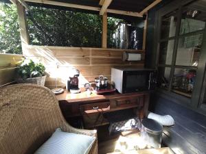 a desk with a microwave and a television on a porch at "Tempat Senang" chalet on the beautiful Veluwe with airco sauna bbq jacuzzi beamer and dog in Putten