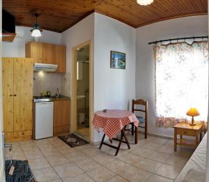 eine Küche und ein Esszimmer mit einem Tisch, einem Tisch und einem Fenster in der Unterkunft Angelos Rooms in Mytilini