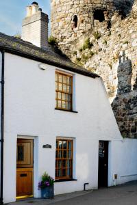 a white house next to a stone building at Harbour Cottage, Conwy in Conwy
