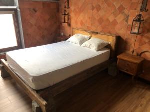 un letto con lenzuola e cuscini bianchi in una stanza di Chez Claude appartement cozy climatisé pour 4 personnes tout confort a Ath