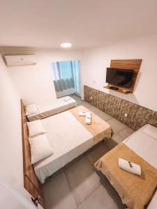 een kamer met 3 bedden en een flatscreen-tv bij IBELLO BEACH Pousada in Cabo Frio