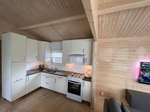 a kitchen with white cabinets and a wooden ceiling at Luxe chalet Beek (gem Montferland) bosrijk, rust en privacy in Beek