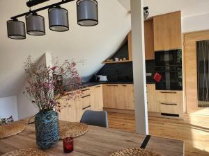 a kitchen with a wooden table with a vase of flowers at Krásný apartmán REFRINO v přírodě in Železná Ruda