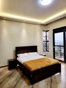 um quarto com uma cama grande e uma janela em Chayil Loft Bahai em Kampala