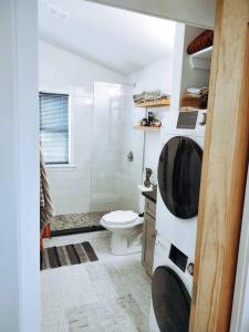 a bathroom with a toilet and a tv on the wall at Modern Treehouse, close to downtown and beach in Wilmington