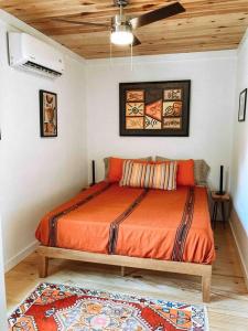 a bedroom with a bed with an orange blanket at Modern Treehouse, close to downtown and beach in Wilmington