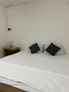 Una cama blanca con dos almohadas negras. en #KangaQHomestay99 en Kangar