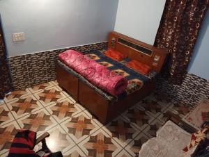 a small bed in a room with a tiled floor at Badal Home Stay @ Jawalaji in Kangra