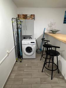 eine Waschküche mit einer Waschmaschine und 2 Hockern in der Unterkunft Appartement agréable et calme in Sainte-Suzanne
