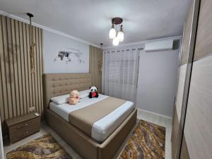 two stuffed animals sitting on a bed in a bedroom at Bala Apartment in Shkodër
