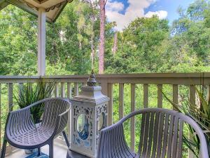 2 Stühle und eine Laterne auf einer Veranda in der Unterkunft Disney 15 min Stunning Enchanted Lake House in Kissimmee