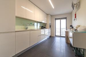 a kitchen with white cabinets and a large window at Palace by Home Sweet Home Aveiro in Aveiro