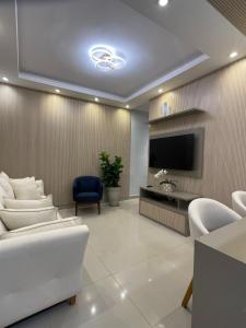 a living room with white furniture and a flat screen tv at Alto Luxo colado no Shopping in Franca