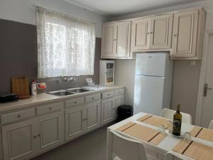 a kitchen with white cabinets and a sink and a table at The house of Nikos and Katerina 2 in Andros
