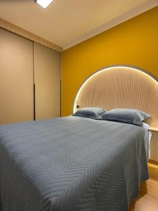 a bedroom with a large bed with a yellow wall at Alto Luxo colado no Shopping in Franca