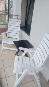 two white chairs and a table on a porch at Apartament Włoski Styl in Gniezno