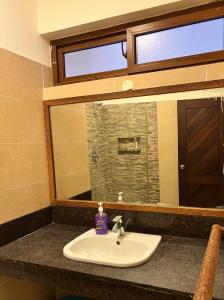 La salle de bains est pourvue d'un lavabo et d'un grand miroir. dans l'établissement Diani Sun Beachfront Studio, à Ukunda