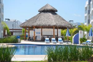a gazebo with chairs and umbrellas next to a pool at Casa Parota Manzanillo in Manzanillo