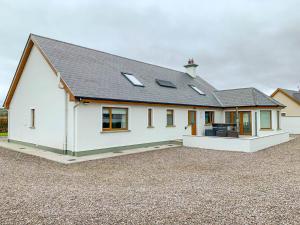 a white house with a roof on a gravel lot at An Ghlaise Bheag in Kilmore