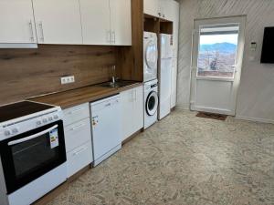a kitchen with white cabinets and a washer and dryer at КЪЩА ЗА ГОСТИ ПЕРЛА in Belogradchik