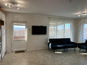 a living room with a couch and a flat screen tv at КЪЩА ЗА ГОСТИ ПЕРЛА in Belogradchik