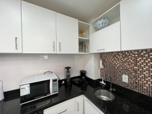 a kitchen with white cabinets and a sink and a microwave at Apartamento em copacabana VISTA MAR in Rio de Janeiro