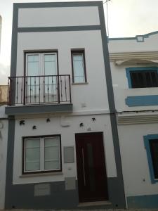 a white building with a balcony and a door at Casa das Andorinhas in Lagos