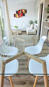 2 sillas blancas y una mesa de cristal en la sala de estar. en Departamento PH en Martinez en Martínez