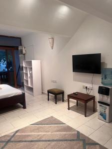 a living room with a bed and a flat screen tv at Diani Sun Beachfront Studio in Ukunda