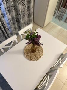 Una mesa blanca con un jarrón con flores. en Etno village Mihailovic en Herceg-Novi