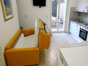 a living room with an orange couch and a kitchen at Grottammare mon amour Lori, con cortile privato in Grottammare
