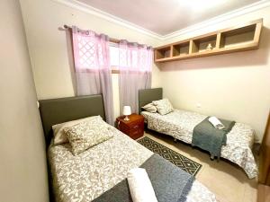 a small bedroom with two beds and a window at Charming 3 bedroom apartment in Playa de San Juan