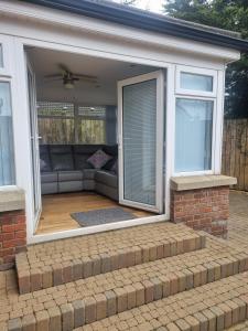 un porche cubierto con sofá y ventana en Sullatober House with hot tub and games room, en Carrickfergus