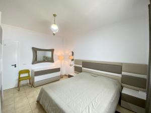 a bedroom with a bed and a mirror and a chair at Delight City Apartment in Kavajë