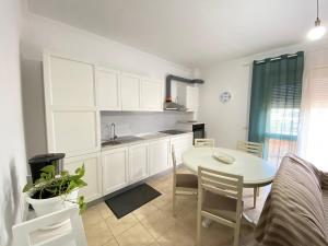 a kitchen with white cabinets and a table and chairs at Delight City Apartment in Kavajë