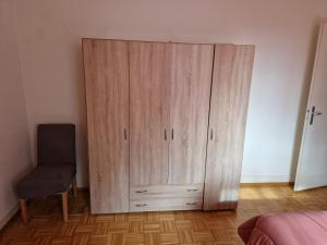 a large wooden cabinet in a bedroom with a chair at La casa de los viajeros in Vevey