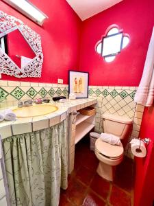 Baño rojo con aseo y lavamanos en Casa Camellia, en San Miguel de Allende