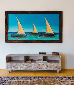 un soggiorno con tavolo e dipinto di barche a vela di Casa Maridadi a Watamu
