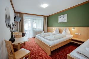 a hotel room with a large bed and a desk at Pension Eschenhof in Kaprun