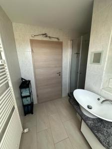 ein Badezimmer mit einem weißen Waschbecken und einer Holztür in der Unterkunft 2,5 Raum Ferienwohnung möbliert Dachgeschoss Niederorschel in Niederorschel