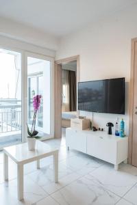 een witte woonkamer met een tv en een tafel bij Queens suite in Thessaloniki