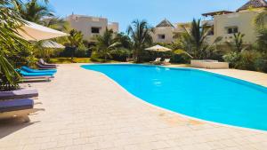 a swimming pool in a resort with chairs and umbrellas at Casa Maridadi in Watamu